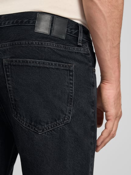 Mannenmodel draagt Jeans met steekzakken model 'Type 2' van Wood Wood, relaxed fit, zwart katoen, detailopname achterzijde.
