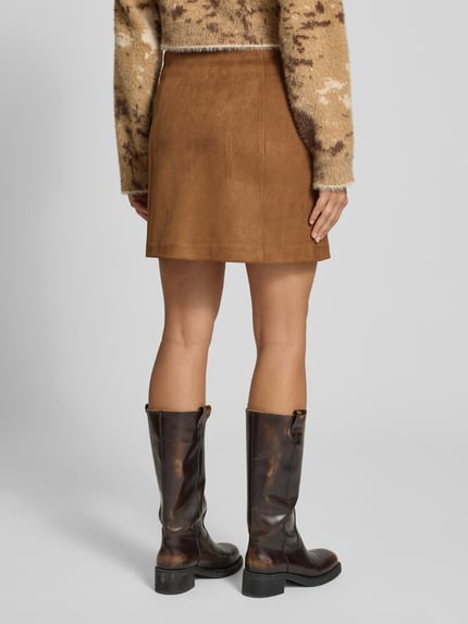Frauenmodel trägt Ausgestellter Mini-Rock mit Teilungsnähten Modell 'DONNAHAZEL' von VERO MODA in Braun, glatte Struktur, Ganzkörperansicht Rückansicht. Damen Mini-Rock von VERO MODA.