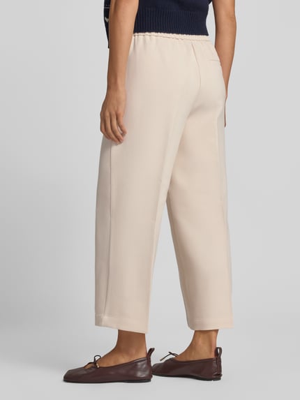 Vrouwenmodel draagt cropped stoffen broek met viscose van someday, straight fit, elastische materiaalmix, bandplooien, steekzakken, achterzak, model 'Curilo', korte look, kleur lichtbeige, bandwijdte maat 36: 39 cm, binnenbeenlengte maat 36: 61 cm, achteraanzicht volledig lichaam.