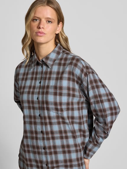 Frauenmodel trägt Relaxed Fit Bluse mit Brusttasche Modell 'JAMIE' von JJXX, kariertes Muster in Braun und Blau, reine Baumwolle, Nahaufnahme Oberkörper. Damen Bluse Allover-Look mit Hemdblusenkragen und Knopfleiste, Kontext: Rückenlänge 76 cm, Ärmellänge 55 cm bei Größe S.