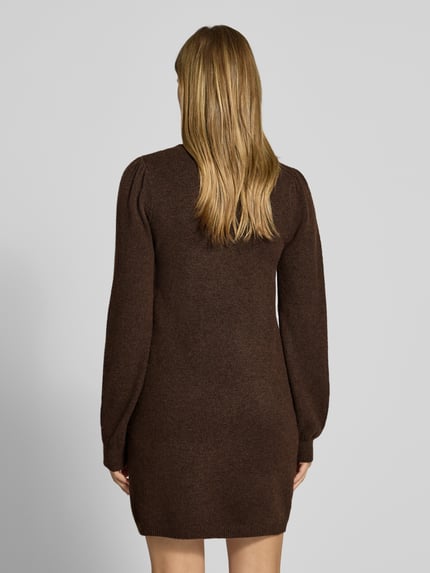 Frauenmodel trägt Strickkleid mit Label-Detail von PIECES in Braun, weiche Stricktextur, Damen Freizeitkleid, Ganzkörperansicht Rückansicht.