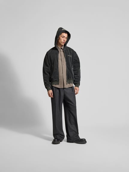 Männermodel trägt Oversized Jeansjacke aus Baumwoll-Mix von Don't Waste Culture, dunkel mit durchgehendem Reißverschluss, Ganzkörperansicht von vorne. Rückenlänge 65 cm, Schulterbreite 58 cm, Ärmellänge 67 cm, Eingrifftaschen mit Druckknopfverschluss, elastische Abschlüsse.