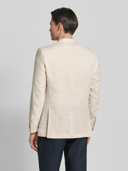 Männermodel trägt Regular Fit Sakko aus Leinen-Mix Modell 'Tebbo' von Carl Gross in Beige, Rückenansicht, natürliche Leinen-Textur, Ganzkörperansicht Rückansicht. Reine Leinen, Brusttasche, AufgesetzteTaschen, Reverskragen, 2-Knopfleiste, Rückenlänge bei Größe 50: 75 cm, Schulterbreite: 43 cm, Ärmellänge: 65 cm.