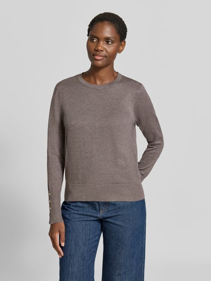 Frauenmodel trägt Strickpullover aus Viskose-Mix Modell 'KATIE' von FREE/QUENT in Braun, glatter Stoff, Knöpfe am Ärmel, gerader Schnitt, Ganzkörperansicht von vorne.