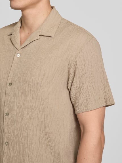 Männermodel trägt Regular Fit Freizeithemd mit Reverskragen von Jack & Jones Premium, beige, strukturierte Baumwoll-Elasthan-Mischung, Nahaufnahme Oberkörper.