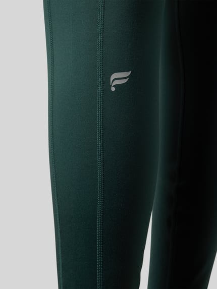 Frauenmodel trägt Slim Fit Leggings mit Logo-Print von Fabletics im Elastischer-Material-Mix, Beintaschen, breiter Bund, Nahaufnahme Oberkörper.