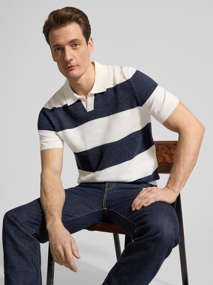 Männermodel trägt Slim Fit Poloshirt aus Baumwoll-Mix in Strick-Optik von OLYMP Level Five, blockstreifen blau-weiß, Nahaufnahme Oberkörper.