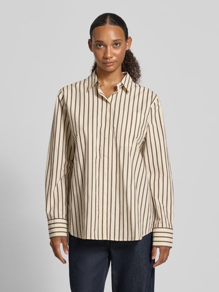Frauenmodel trägt Loose Fit Langarmbluse aus reiner Baumwolle von ARMEDANGELS, beige mit braunen Streifen, Ganzkörperansicht von vorne.
