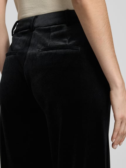 Frauenmodel trägt Regular Fit Hose aus Samt mit Eingrifftaschen von Jake*s Collection in Schwarz, strukturierte Optik, Nahaufnahme Rückansicht.