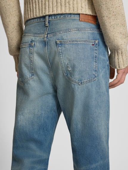 Männermodel trägt Tapered Fit Jeans aus reine katoen Modell 'SONNY' van Tommy Jeans in denim used look met label patch detail, detailopname rugaanzicht.