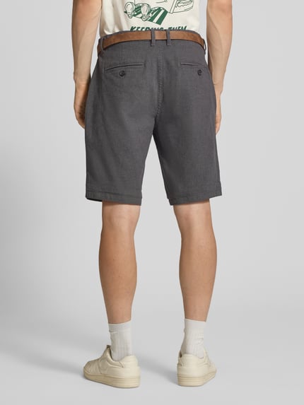 Männermodel trägt Bermudas mit Gürtel und Eingrifftaschen Modell 'NEBRASKA' von Redefined Rebel aus Baumwoll-Mix mit Stretch-Anteil, Ganzkörperansicht Rückansicht.