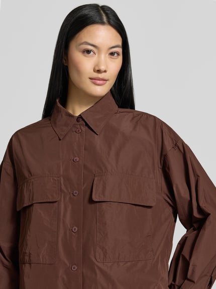 Frauenmodel trägt Relaxed Fit Jacke mit Brusttaschen von Luisa Cerano in Braun, Umlegekragen, glatte Struktur, Nahaufnahme Oberkörper.