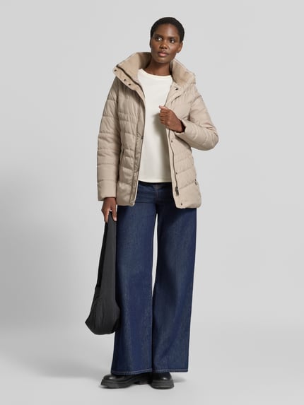 Kobiece modelka nosi 'Jacke in Stepp-Optik mit Kapuze' od FUCHS SCHMITT, beżowa, z efektem pikowania, taliowany krój, kaptur, ocieplany stójka, wpuszczane kieszenie z zamkiem błyskawicznym, długość tyłu w rozmiarze 36: 74 cm, szerokość ramion w rozmiarze 36: 40 cm, szerokość klatki piersiowej w rozmiarze 36: 48 cm, długość rękawów w rozmiarze 36: 64 cm, cała sylwetka z przodu.