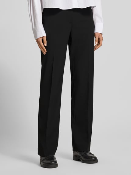 Frauenmodel trägt Regular Fit Schlaghose mit Bügelfalten von Tommy Hilfiger, unifarben in Schwarz, Slim Fit, seitliche Eingrifftaschen, Nahaufnahme Unterkörper.