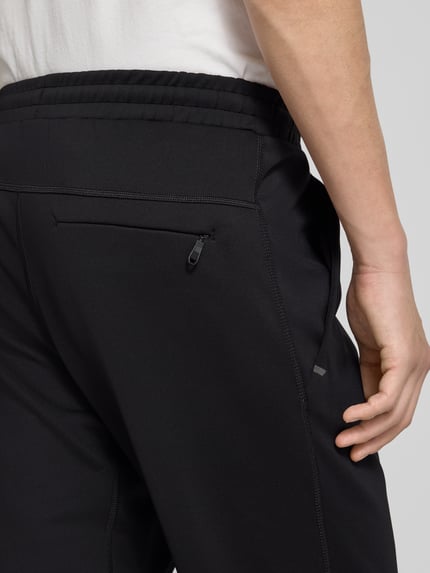 Mężczyzna nosi Regular Fit Spodnie dresowe z szybkoschnącego materiału Model 'HICON ACTIVE' od BOSS Green, efekt: jednolity kolor, elastyczny ściągacz, wpuszczane kieszenie, kieszeń z tyłu, nadruk z logo, flatlockowe szwy, detal z materiału Tech. Detailaufnahme.