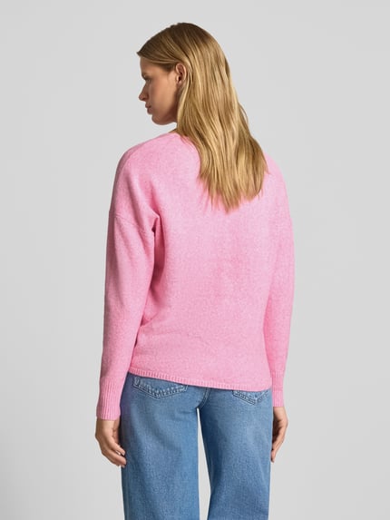 Frauenmodel trägt Relaxed Fit Pullover mit V-Ausschnitt von ONLY in Rosa, kombiniert mit blauen Jeans, Ganzkörperansicht Rückansicht. Damen Pullover von ONLY.