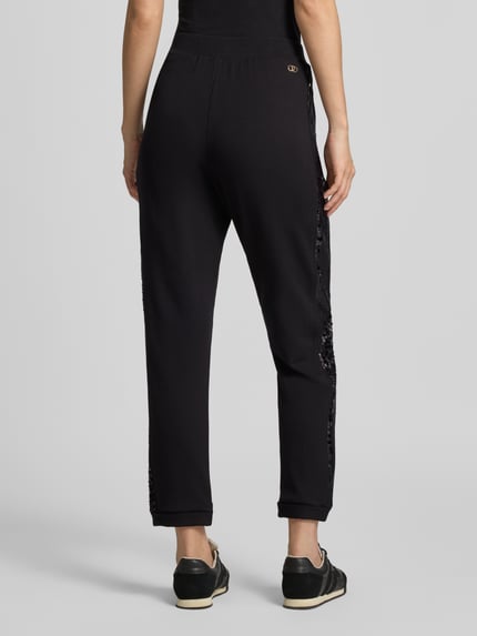 Frauenmodel trägt Sweatpants aus Viskose-Elasthan-Mix mit Pailletten von Liu Jo in Schwarz, elastischer Bund, Ganzkörperansicht Rückansicht.