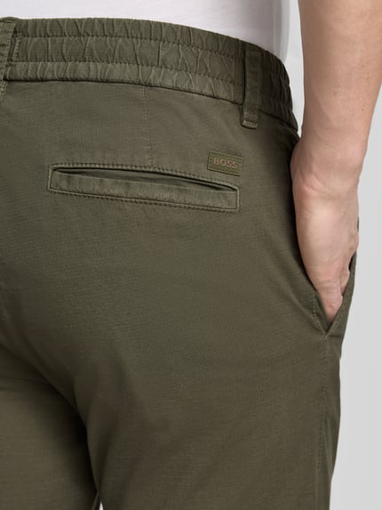 Männermodel trägt Tapered Chino aus Baumwoll-Mix Modell 'CHINO-TAPERED-DS-10' von BOSS Orange, unifarben, Nahaufnahme Rückansicht.