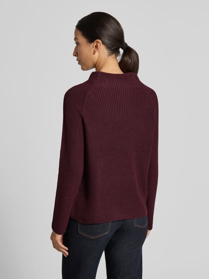 Frauenmodel trägt Strickpullover mit Stehkragen von monari in dunklem Beerenrot, Grobstrick, Regular Fit, Baumwoll-Mix, Ganzkörperansicht Rückansicht.