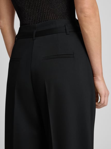Frauenmodel trägt Stoffhose mit Gesäßtaschen von More & More, schwarzer Material-Mix, lockerer Schnitt, Nahaufnahme Rückansicht