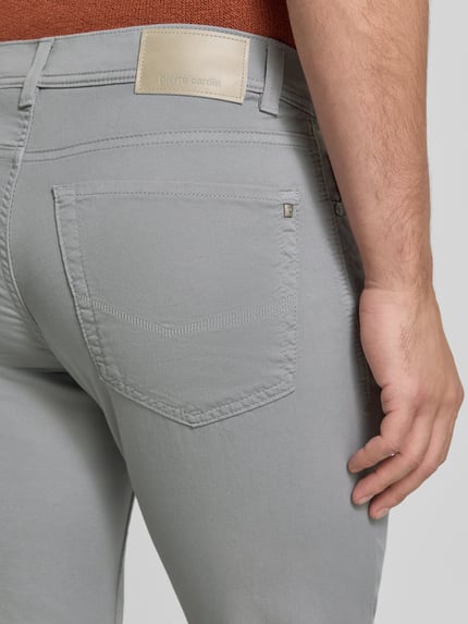 Mężczyzna nosi Tapered Fit Hose mit Eingrifftaschen Modell 'Lyon' od Pierre Cardin, mieszanka bawełny i elastanu, wpuszczane kieszenie, model męski, Szerokość w rozmiarze 32/32: 41 cm, Długość wewnętrzna nogawki w rozmiarze 32/32: 80 cm, szare, detal tylnej kieszeni, zbliżenie na tył