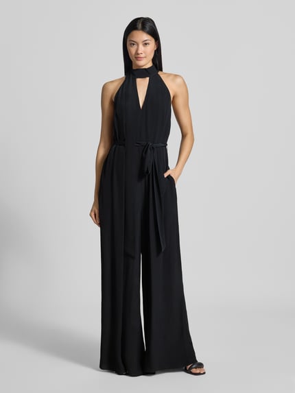 Frauenmodel trägt Regular Fit Jumpsuit aus reiner Viskose Modell 'Chiva' von Ted Baker in Schwarz mit Zierschleife, Ganzkörperansicht von vorne.