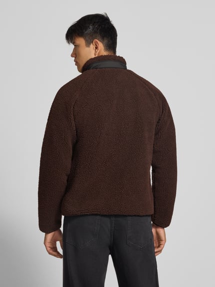 Männermodel trägt Teddyjacke mit Brusttasche Modell 'PRENTIS LINER' von Carhartt Work In Progress, braune Fleece-Struktur, Ganzkörperansicht Rückansicht.
