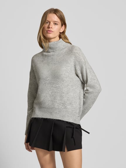 Frauenmodel trägt Oversized Rollkragenpullover mit Paillettenbesatz Modell 'ARIZONA LS SEQUINS' von Only in Hellgrau, Strickoptik, unifarben, Effektgarn, Rippenabschlüsse, Applikation, Ganzkörperansicht von vorne.
