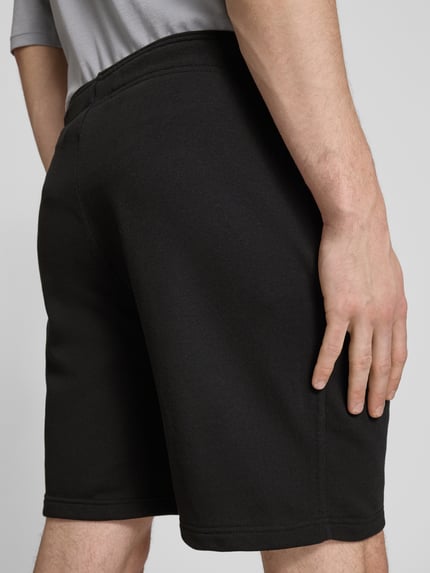 Mężczyznamodel nosi Shorts mit elastischem Bund und Label-Stitching od CHAMPION, czarny, bawełniany miks, krój regular fit, szerokość w rozmiarze M: 43 cm, długość wewnętrzna nogawki w rozmiarze M: 17 cm, detaliczne przeszycia, widok z tyłu, zbliżenie na dolną część pleców i uda.