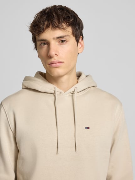 Männermodel trägt Regular Fit Hoodie aus Baumwoll-Mix van Tommy Jeans, beige, fleece, logo-stiksel, Nahaufnahme Oberkörper.