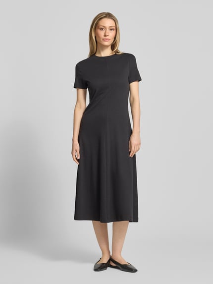 Frauenmodel trägt Midikleid aus reiner Baumwolle von Tommy Hilfiger in Unifarbe Schwarz, Regular Fit, Rundhals, kurzarm, Logo-Stitching, Ganzkörperansicht von vorne.