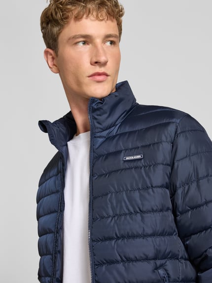 Männermodel trägt Jacke mit Label-Patch Modell 'ELVIS' von JACK & JONES in Dunkelblau mit Stehkragen, Nahaufnahme Oberkörper.