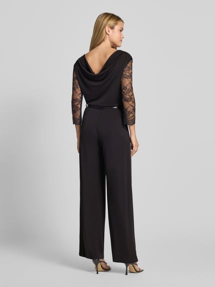 Vrouwenmodel draagt Regular Fit jumpsuit met kant van Rinascimento in zwart met V-hals, plooien, 3/4-mouw, ruglengte maat S 37 cm, borstwijdte 36 cm, mouwlengte 47 cm, totale lengte 158 cm, binnenbeenlengte 87 cm, helemaal van achteren