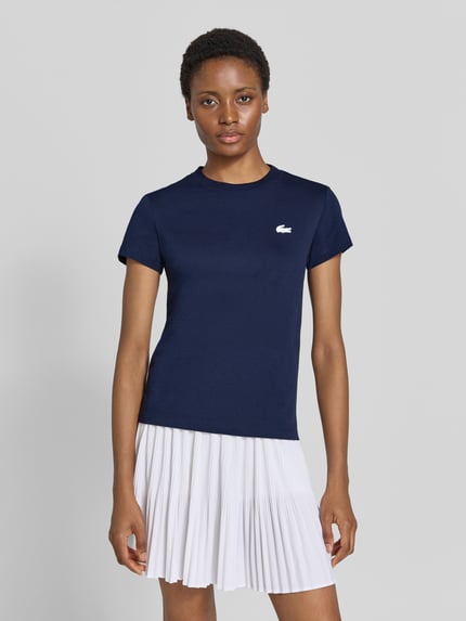 Modelka kobieca ma na sobie navy Slim Fit Sport-T-Shirt aus Baumwoll-Mix von Lacoste, lekko prążkowana struktura, Lacoste Sport, widok całej sylwetki z przodu.
