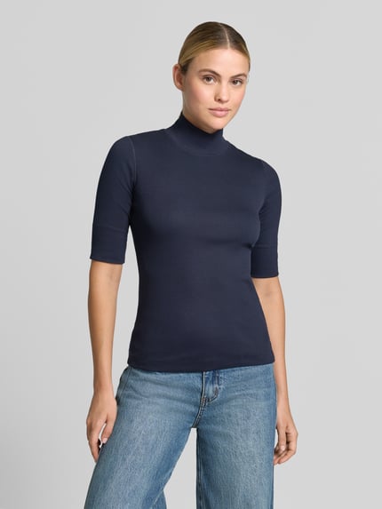 Kobiece model prezentuje Slim Fit Longsleeve aus Baumwoll-Mix von Marc Cain, granatowy, stójka, rękaw o dł. 1/2, mieszanka bawełny, długość tyłu w rozmiarze 36: 58 cm, bluzka z długim rękawem, widok na cały przód.