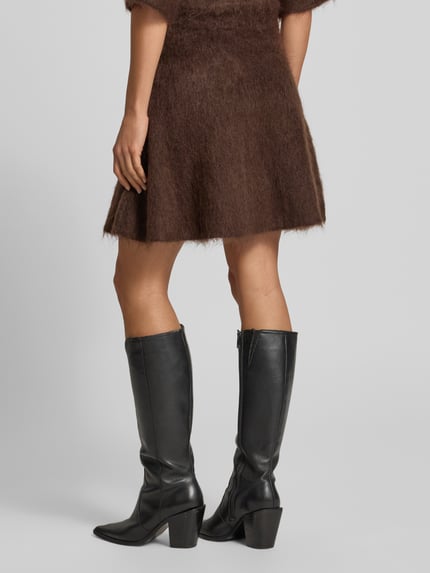 Frauenmodel trägt Strickrock mit elastischem Bund Modell 'TILDE' von YAS, braun, A-Linie, strukturierte Oberfläche, Ganzkörperansicht Rückansicht. Material-Mix mit Mohair-Anteil, Minirock.