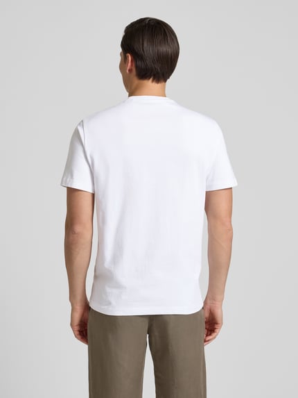 Männermodel trägt T-Shirt mit Logo und Rundhalsausschnitt von Guess aus reiner Baumwolle in Weiß, Regular Fit, Ganzkörperansicht Rückansicht.