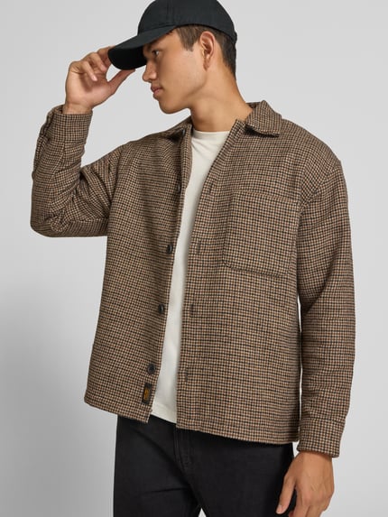 Männermodel trägt Regular Fit Hemdjacke mit Brusttasche Modell 'SOHO OLLIE' von JACK & JONES, braun gemustert, Ganzkörperansicht von vorne. Kontext: Herren Hemdjacke, Kentkragen, durchgehende Knopfleiste, Rückenlänge 71 cm, Schulterbreite 41 cm, Ärmellänge 65 cm.