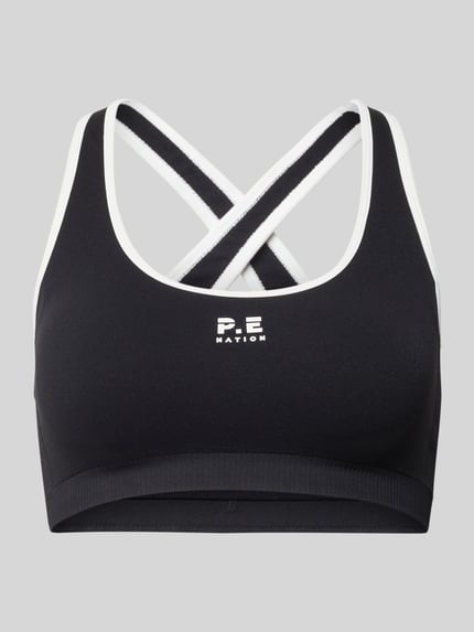 Produktfoto, schwarzer Sport-BH mit weißem Logo-Print, Rundhalsausschnitt, überkreuzte Träger, Modell 'ADAPTION SEAMLESS' von P.E Nation, elastisches Material