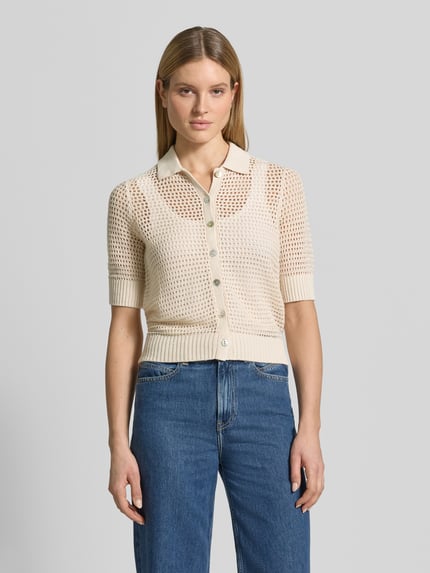 Kobiece modelka nosi Strickjacke aus Leinen mit 1/2-Arm od Christian Berg Woman, kremowy kolor, ażurowa tekstura, krój slim fit, polo kołnierz, pełny zapięcie na guziki, rękaw 1/2, długość tyłu 59 cm, długość rękawa 34 cm, widok całej sylwetki z przodu.