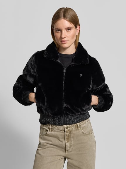Vrouwenmodel draagt Jacke aus Kunstfell mit Stehkragen Modell 'CARLA' van GUESS Activewear in zwart, regular fit, rits, voorkant, bovenlichaam close-up.