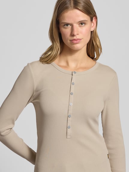 Frauenmodel trägt Slim Fit Longsleeve mit Rundhalsausschnitt und Knopfleiste von G-Star Raw im Baumwoll-Elasthan-Mix, beige, Nahaufnahme Oberkörper.