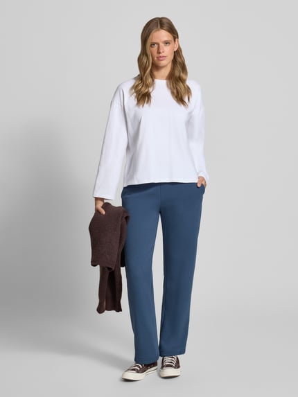 Frauenmodel trägt Sweatpants aus Baumwoll-Mix mit Tunnelzug Modell 'Iconic' von Gina Tricot in Blau, Straight Fit, elastischer Bund, Ganzkörperansicht von vorne.