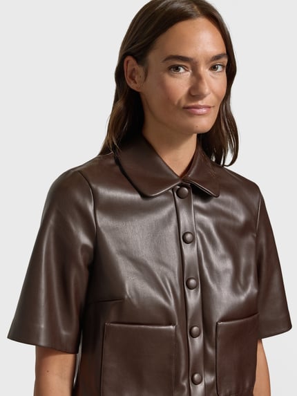 Frauenmodel trägt Cropped Hemdbluse in Leder-Optik von Christian Berg Woman Selection, knöpfbar, aufgesetzte Taschen, Nahaufnahme Oberkörper.