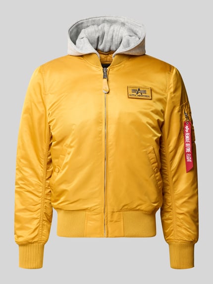Produktfoto, Regular Fit Bomberjacke mit Kapuze von Alpha Industries, żółta tkanina, żebrowane wykończenia, kieszenie, detal z logo, krój regular fit, kaptur, suwak, długość tyłu w rozmiarze M: 64 cm, szerokość ramion w rozmiarze M: 47 cm, szerokość klatki piersiowej w rozmiarze M: 55 cm, długość rękawa w rozmiarze M: 68 cm