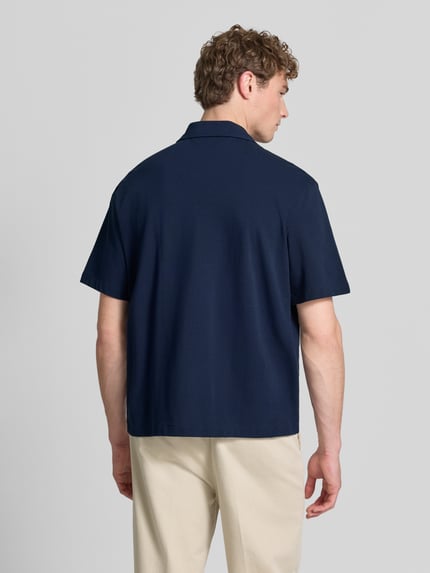 Männermodel trägt Relaxed Fit Freizeithemd aus reiner Baumwolle von Lacoste in Dunkelblau, kurzarm, unifarben, Ganzkörperansicht Rückansicht.