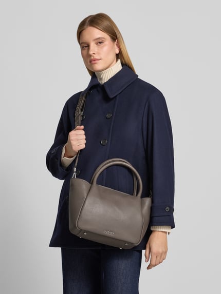 Frauenmodel trägt Handtasche mit Tragehenkel und Schulterriemen von BOGNER, grau, strukturierte Oberfläche, Ganzkörperansicht von vorne. Damen Handtasche Modell 'wallis raja' mit Label-Applikation, Hauptfach mit Reißverschluss, Breite 39 cm, Länge 21 cm, Tiefe 11 cm, Länge Schulterriemen 40 cm.