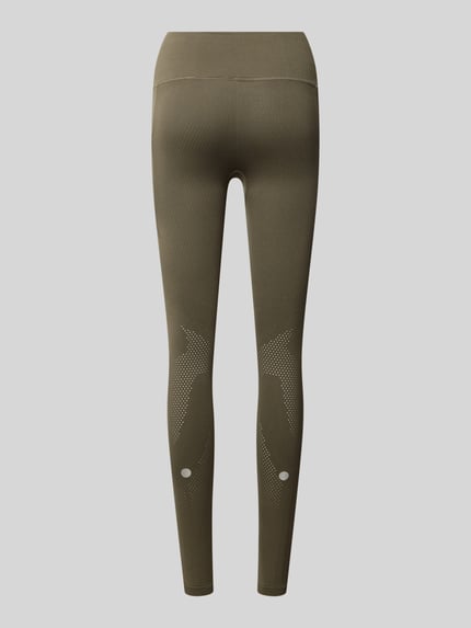 Frauenmodel trägt Slim Fit Leggings mit Logo-Print von ASICS in Olivgrün mit elastischem Bund und Struktur-Partien, Ganzkörperansicht Rückansicht.