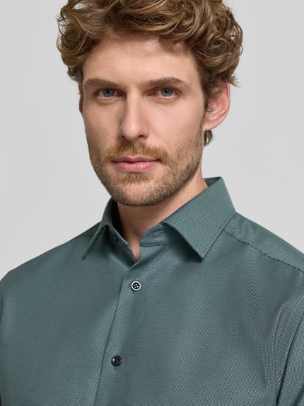 Mannelijk model draagt Modern Fit zakelijk overhemd met extra lange mouw van OLYMP, groene tint, fijn patroon, Nahaufnahme Oberkörper. Heren Businesshemd von OLYMP.