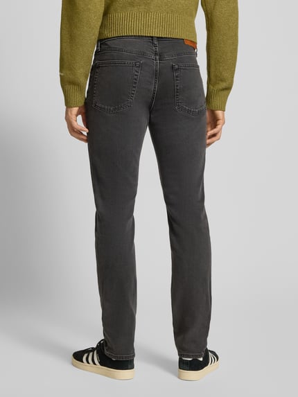 Männermodel trägt Slim Fit Jeans mit Label-Detail von Calvin Klein Jeans, grauer Baumwoll-Elasthan-Mix mit Eingrifftaschen, Ganzkörperansicht Rückansicht.